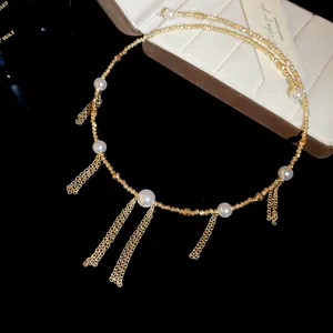 Detailed close-up of a gold pearl tassel choker necklace with intricate metallic chains