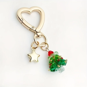 Golden heart-shaped keychain with beaded Christmas tree and star charm on white background