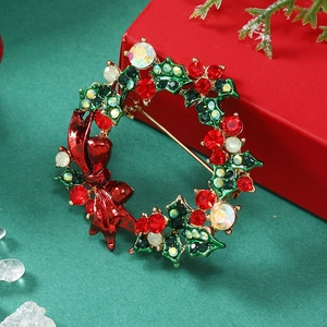 Detailed view of rhinestone Christmas wreath brooch with red bow on a festive background