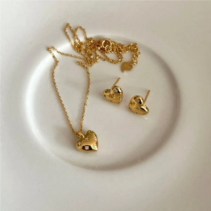 Detail of 925 sterling silver heart necklace and earrings set with zircons in gold finish