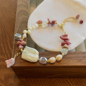 Baroque pearl and pink rose quartz adjustable bracelet on a wooden jewelry display case