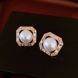 Macro shot of French gold-plated hexagonal earrings with central pearl and sparkling zircons