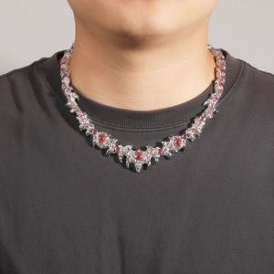Macro detail of silver claw necklace with inlaid red gemstone on male model neck