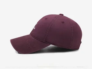 Side view of wine red cotton baseball cap with white script embroidery and eyelets