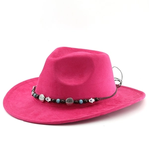 Détail d'un chapeau de cowboy fuchsia avec ceinture ethnique et breloques bohèmes