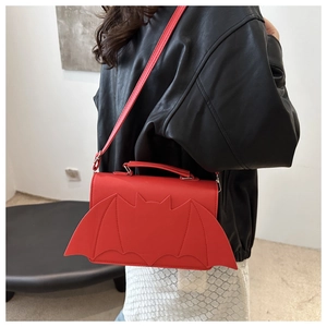 Detail of red bat-shaped crossbody bag with wings made of PU leather on a model