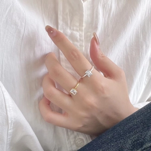 Minimalist 925 silver open ring with square zircon worn on hand against white linen fabric