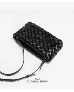 Close-up of black woven leather handbag with wide straps and gold hardware detail