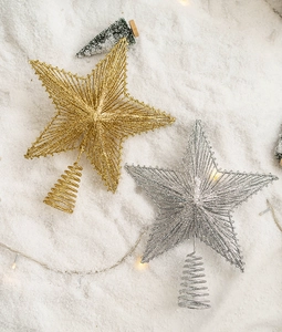 Detail of glitter gold and silver iron star toppers with spiral base on snowy background
