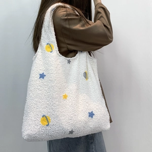 Detail of white fleece tote bag with colorful planet and star embroidery textures