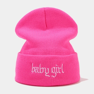 Detail der pinkfarbenen Strickmütze mit weißer baby girl Stickerei in Gothic-Schrift
