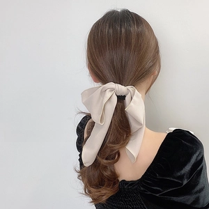 Elegant beige bow hair tie shown on a ponytail with soft chiffon fabric detail