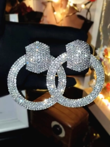Macro shot of silver oversized double hoop earrings fully paved with sparkling rhinestones
