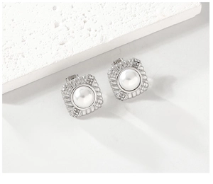 Close-up of square silver stud earrings featuring a center pearl and rhinestone accents
