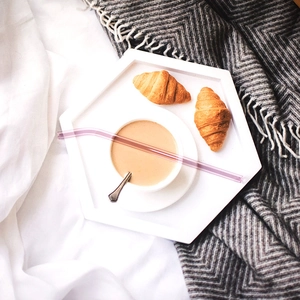Eco-friendly curved purple glass straw shown on a breakfast tray with coffee and croissants