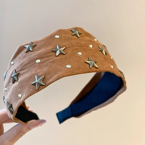 Détail d'un serre-tête en velours marron avec des rivets étoiles argentés et texture