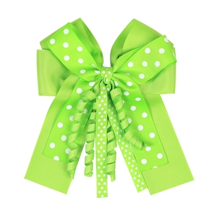 Close-up of green polka dot ribbon hair bow with elegant curly streamers on white background