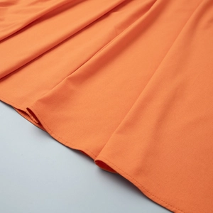 Detailed close-up of orange cotton linen skirt hemline showing smooth fabric and neat stitching