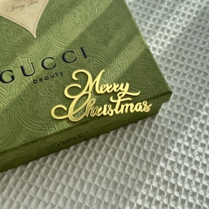 Close-up of golden acrylic Merry Christmas cake topper on luxury green perfume box