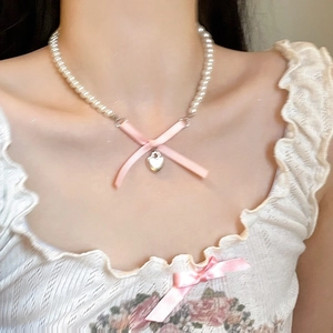 Detail of pink satin bow and silver heart locket on a delicate white pearl choker necklace