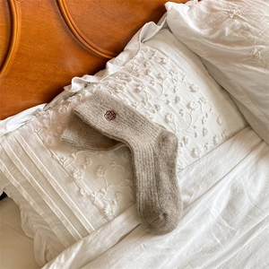 Detailed macro view of beige wool socks featuring delicate floral embroidery on fabric