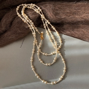 Detail view of a multi-layer faux pearl necklace with a polished gold metal clasp