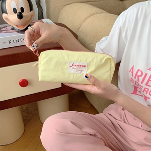 Detail of yellow Macaron pencil case with pink zipper held by hand in a cozy setup