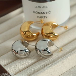 Polished gold and silver crescent moon stud earrings displayed on a velvet jewelry tray