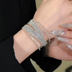 Detailopname van een glinsterende zilveren meerlaagse strass-armband om de pols