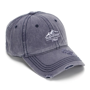 Détail macro de la casquette en coton bleu-gris délavé avec broderie vintage vieillie