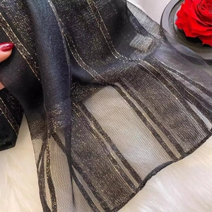 Detail of silk wool scarf showing black sheer fabric with elegant gold metallic stripes