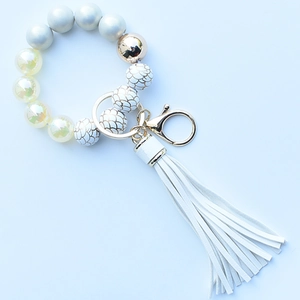 Close-up of leopard silicone beads and white PU tassel keychain with golden metal ring