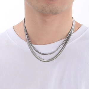 Close-up of minimalist silver snake chain necklaces layered on a model's neck