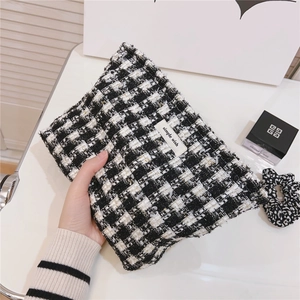 Gros plan d'une trousse de maquillage en tweed noir et blanc avec fils dorés et étiquette