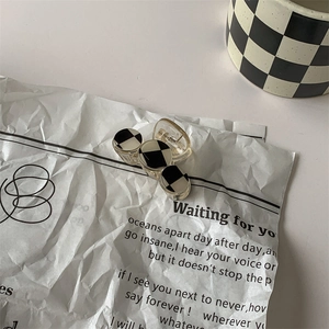 Detail shot of mini black and white checkered hair claw clip on vintage lyric paper