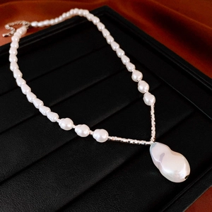 Détail du collier de perles baroques et chaîne argentée sur présentoir en velours