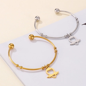 Detail of gold and silver open bracelets featuring unique heart-wing charms on a display card