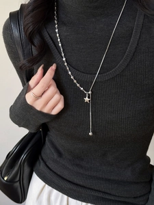 Silver Y-shaped star necklace and minimalist double ring set on a black sweater