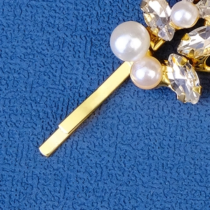 Macro view of crystal and pearl leaf hairpin with gold metallic claw setting