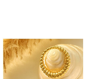 Detailed close-up of golden twisted rope ring on a shell for natural accessory aesthetic