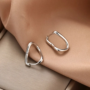 Boucles d'oreilles argentées torsadées en forme de U sur soie champagne