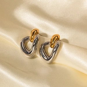Détail de boucles d'oreilles bicolores or et argent sur un fond en soie dorée brillante