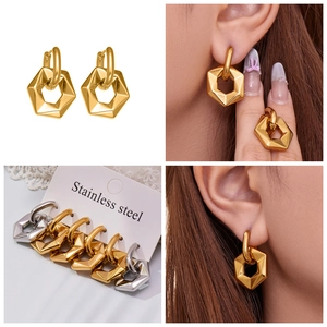 Detailed close-up of hollow hexagonal hoop earrings in polished gold and silver finishes