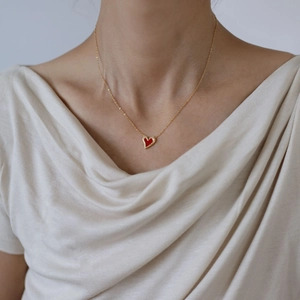 Close-up of a gold-plated titanium steel necklace featuring a red heart pendant on a model