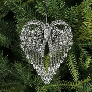 Transparent crystal angel wings Christmas ornament hanging on a pine tree branch