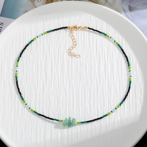 Detailed top view of handmade beaded necklace with green natural stones on white tray