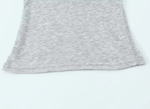 Detail of grey knitted T-shirt hem showing stitching process and fabric texture