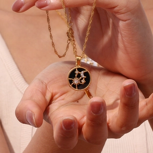 Detailed close-up of 18K gold plated sun and moon pendant with sparkling zircon accents