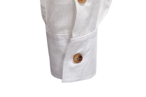Close-up of white long sleeve shirt cuff with textured fabric and brown resin buttons