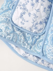 Detail of floral and paisley quilted fabric with blue piping on the lapel and pocket